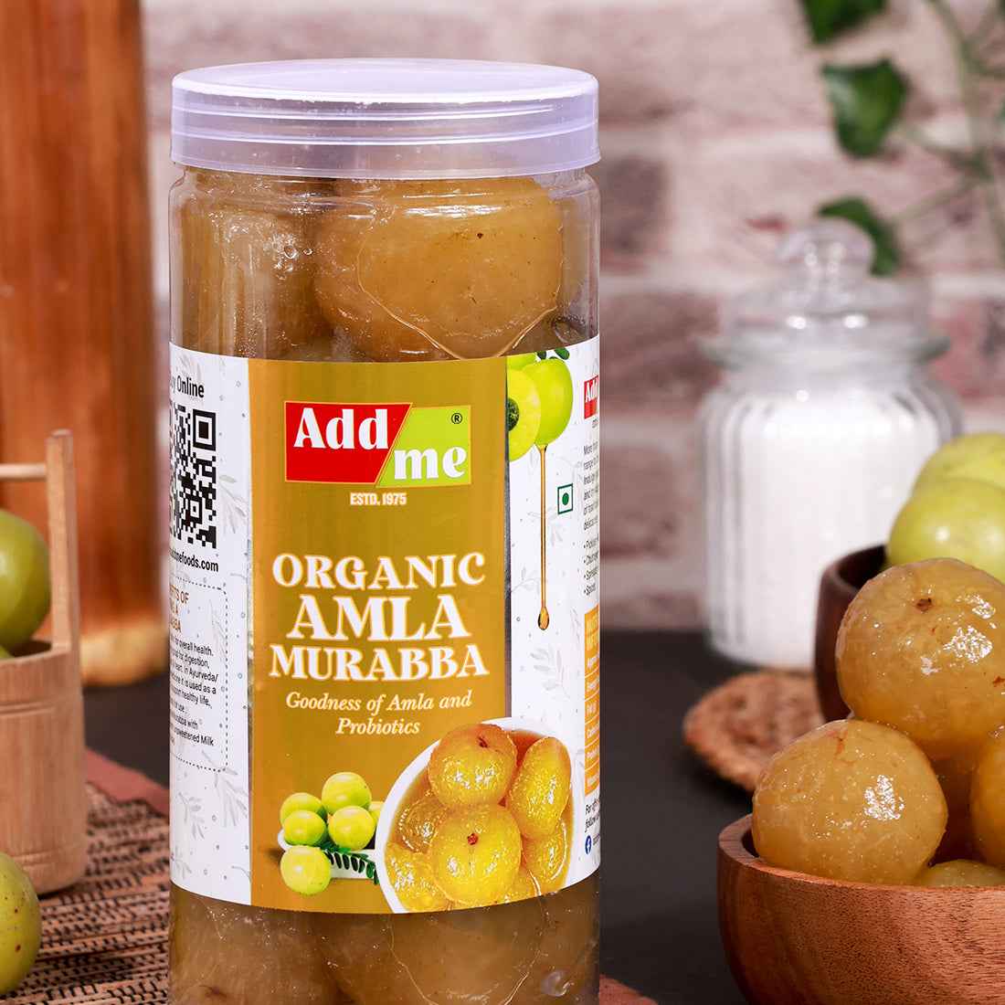 Add Me Foods: Jar of Add Me Organic Amla Murabba with a QR code on the label, surrounded by green and yellow fruits.