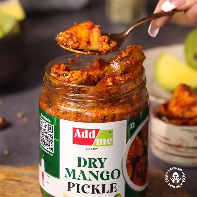 Jar of Add Me Dry Mango Pickle with a spoonful being lifted, surrounded by fruits. Mango pickle, sukha aam ka achar