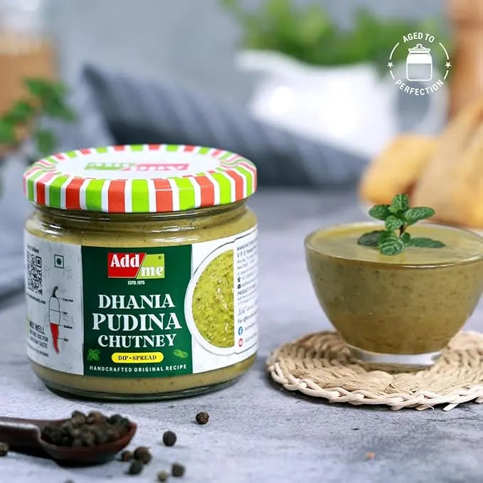 Jar of Add Me Dhania Pudina Chutney with a bowl of chutney and ingredients on a table.