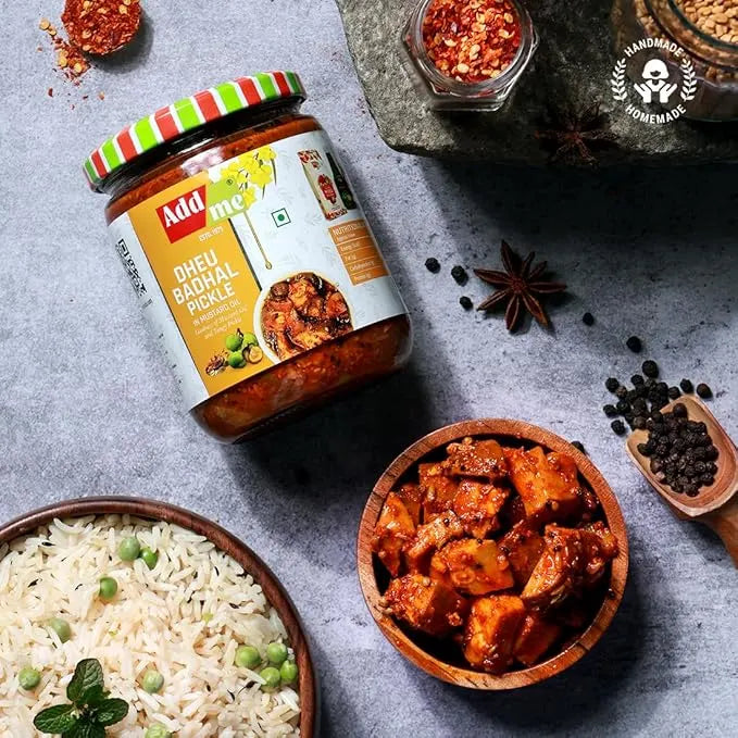 Jar of Dhabal pickle with a bowl of rice and pickled items on a gray surface.