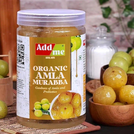 Jar of Add Me Organic Amla Murabba with a bowl of amla fruits on a wooden surface.
