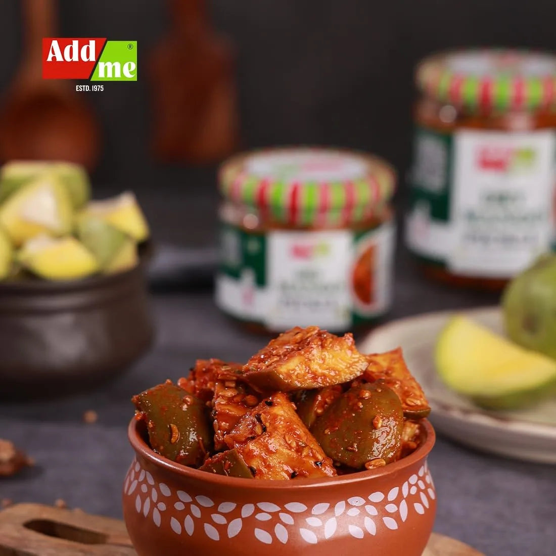 Spicy Mango Pickle in a decorative bowl with jars and ingredients in the background, featuring Addme branding.