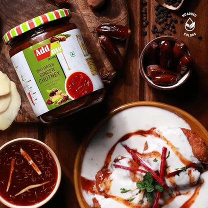 Jar of Adame Imli Dates Ginger Chutney on a wooden board with food items around