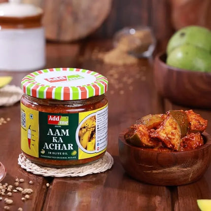 Jar of Aam Ka Achar with a bowl of pickled aam on a wooden table