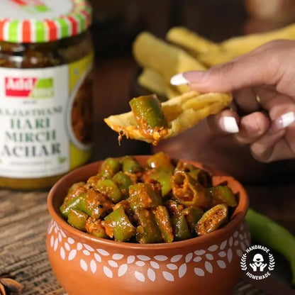 Add Me Foods: Person dipping a chip into a bowl of green chilies with a jar of Aashirwad Mirch Achar in the background.