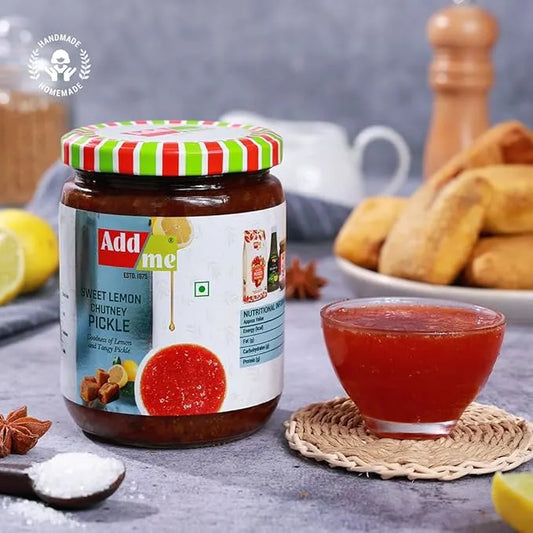 Jar of Add Me sweet lemon chutney pickle with a small bowl of red chutney on a table.