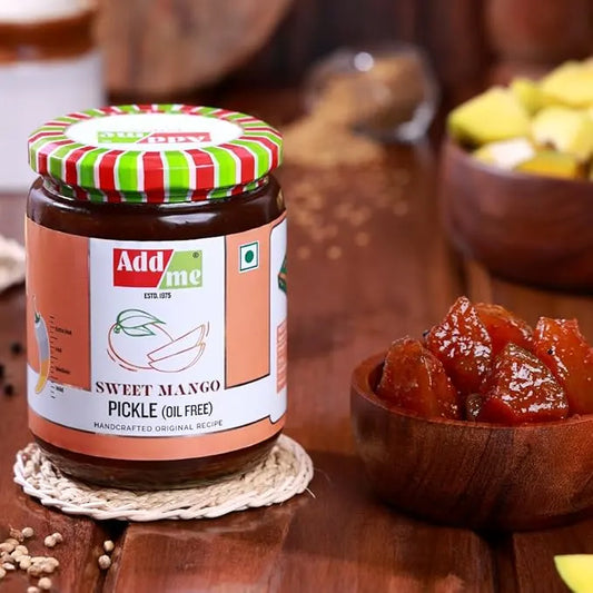 Jar of Add Me Sweet Mango Pickle on a wooden surface with a bowl of pickle.